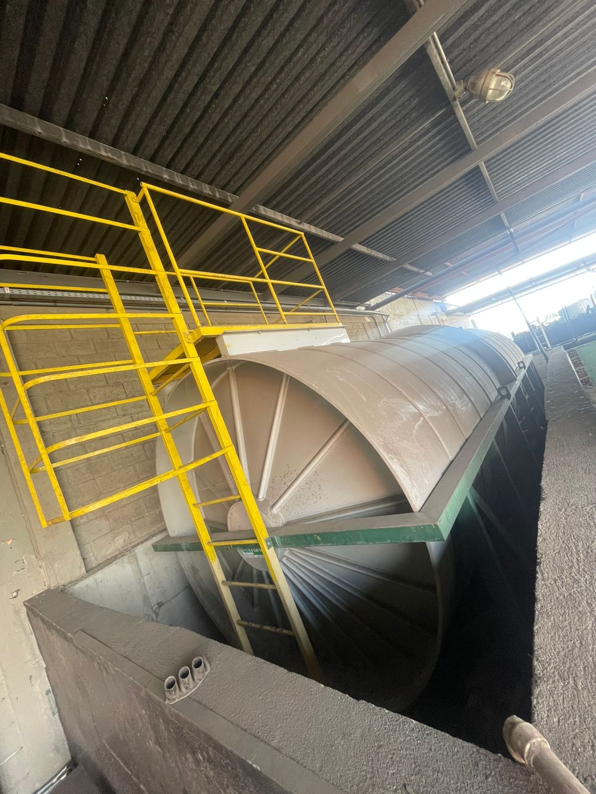 Tanque horizontal de combustível em galpão industrial — vista lateral com escada amarela de segurança