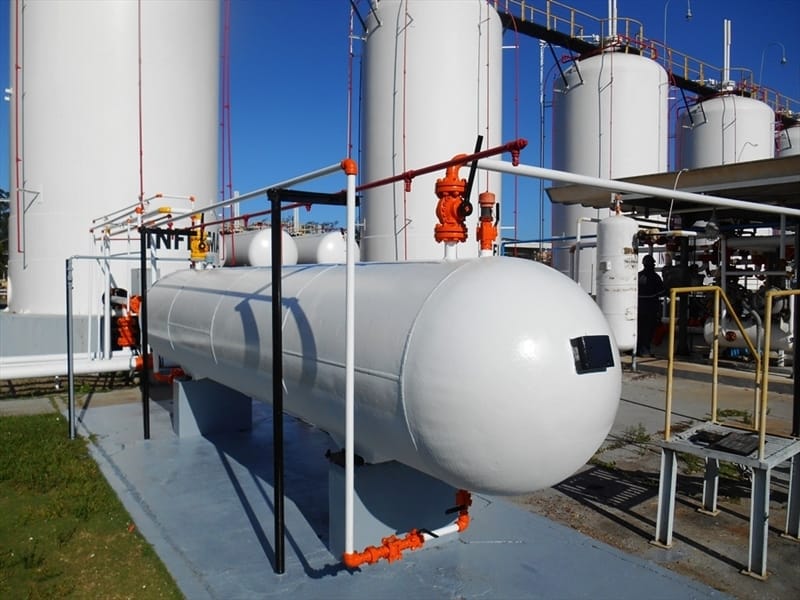 Vaso de pressão horizontal com tubulações laranja em área industrial